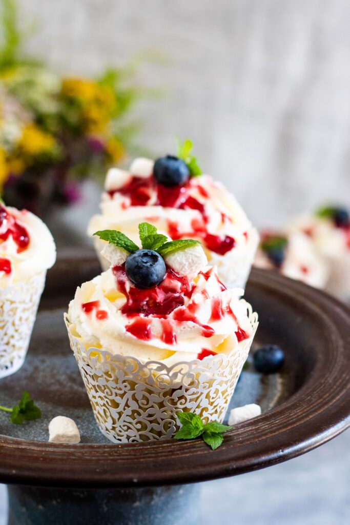 upieczone muffinki z kremem maślanym ozdobione borówką miętą i konfitura